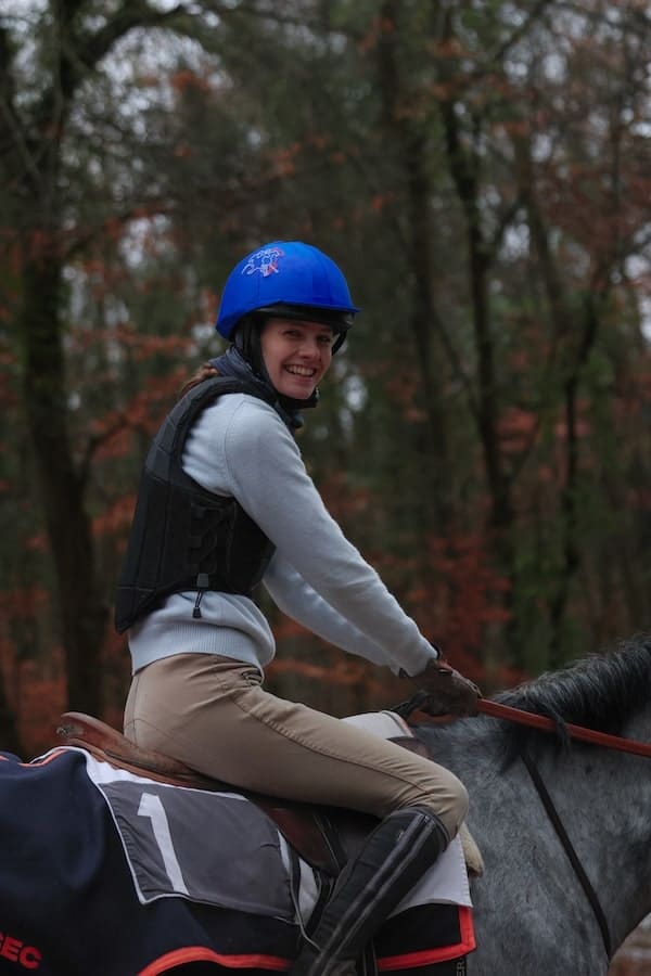 Aurore, jeune cavalière icessienne, regarde la caméra depuis sa selle en souriant